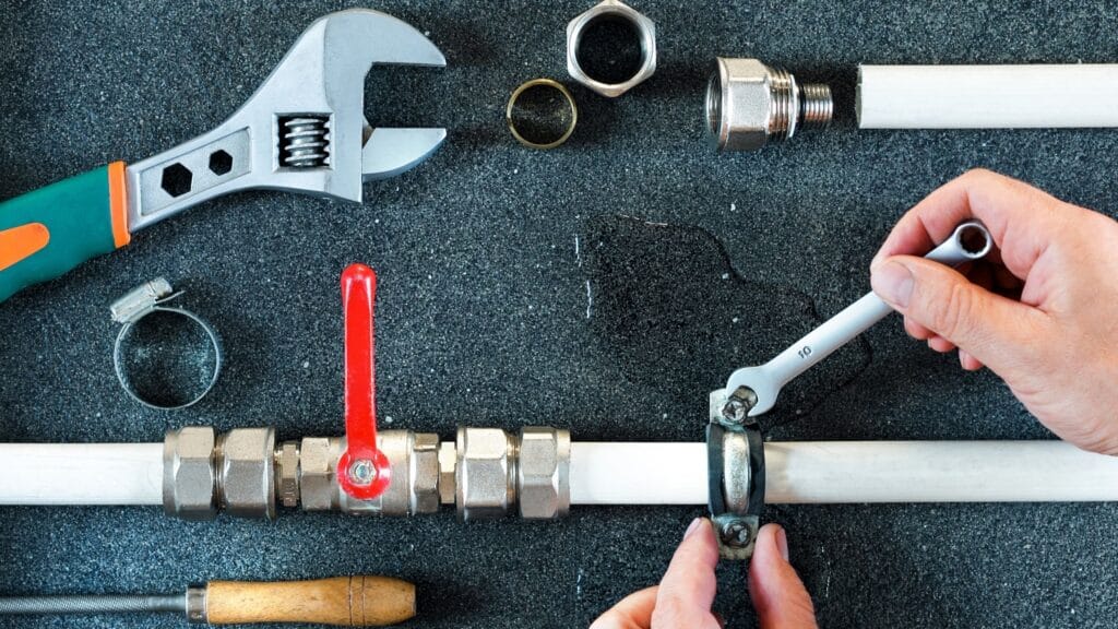 Plumber repairing a pipe valve with an adjustable wrench in Salinas