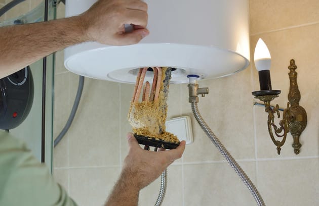 Technician removing mineral buildup from a water heater in Salinas