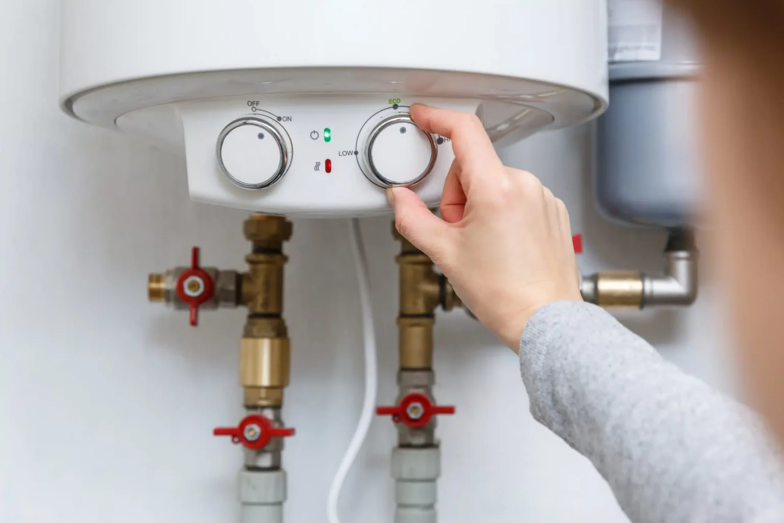 Homeowner adjusting the temperature controls on a water heater in Salinas